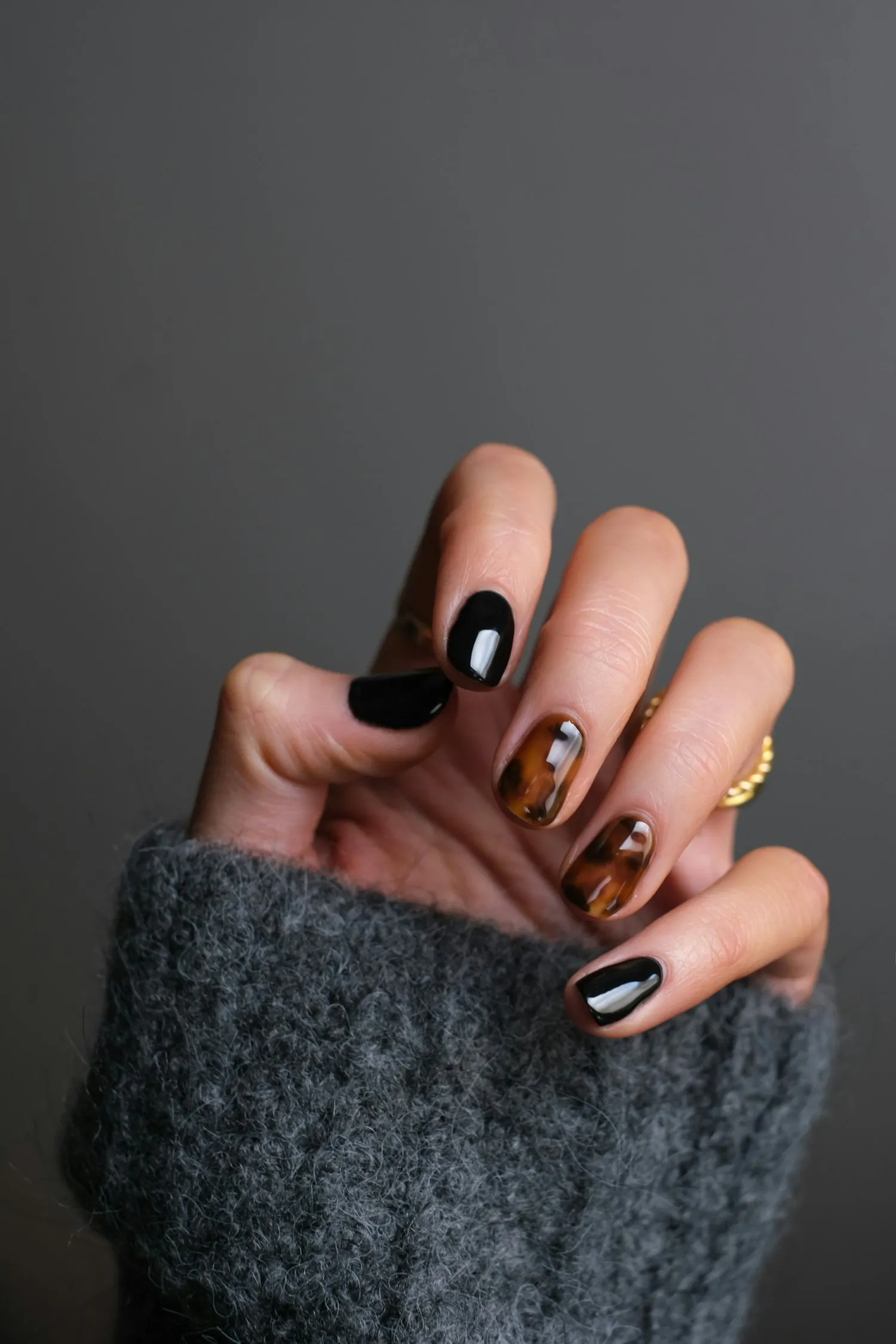 Detalle de una manicura artística en tonos oscuros y carey